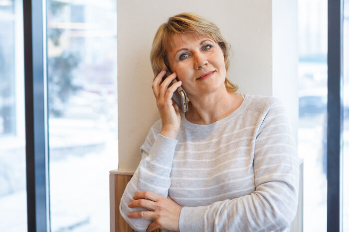Middle-aged woman with a calm expression using a phone, representing Karen unhinged parents diabolical theme.