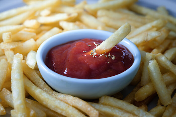 French fries dipped in ketchup with a focus on a single fry, illustrating karen unhinged parents diabolical behavior concept.