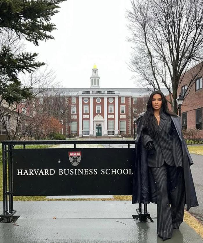 Kim Kardashian standing outside Harvard Business School dressed in a black pinstripe suit celebrating law school graduation.
