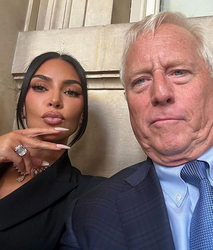Kim Kardashian posing with a man, wearing a black outfit and large jewelry during Paris jewelry heist trial.