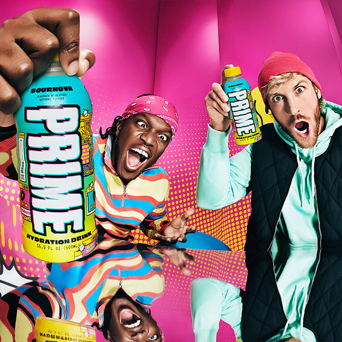 KSI and Logan Paul excitedly holding Prime hydration drinks in a vibrant room highlighting KSI&rsquo;s net worth and Prime stake.