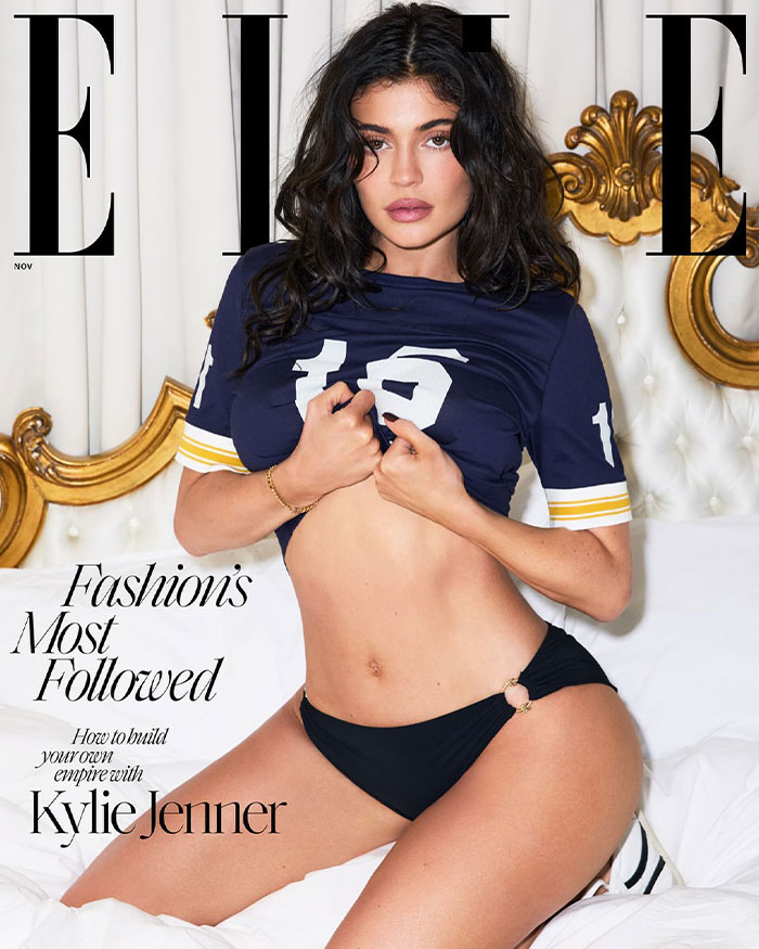 Kylie Jenner posing in a blue sports top and black bikini bottoms for a fashion magazine cover photo.
