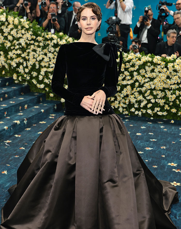 Woman in a black velvet top and voluminous skirt at Met Gala 2025, with dramatic weight loss revealed, sponsored by Ozempic.