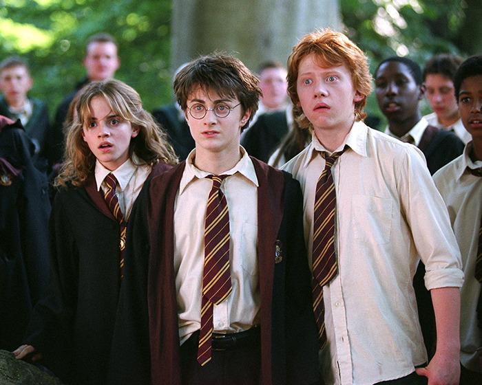 Harry, Hermione, and Ron in Hogwarts uniforms, looking surprised during a scene from the upcoming Harry Potter series cast reveal.
