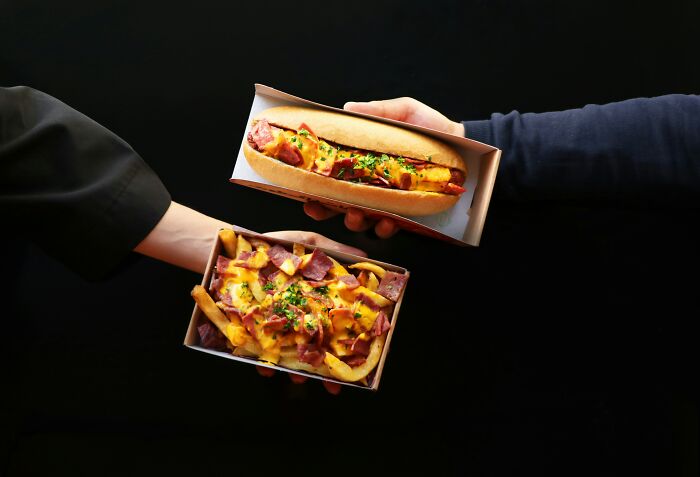 Two hands holding fast food items with melted cheese and bacon against a black background, illustrating body changes.
