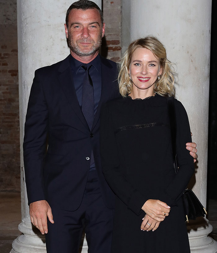 Liev Schreiber in a dark suit and Naomi Watts in a black dress posing at an event, highlighting support for transgender issues.