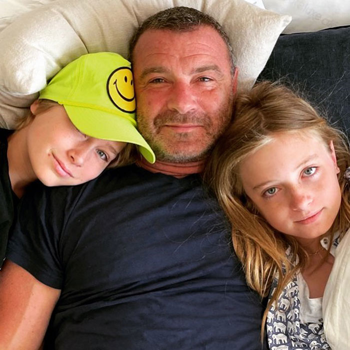 Liev Schreiber lying with his two children, showing support for his teen daughter coming out as transgender.