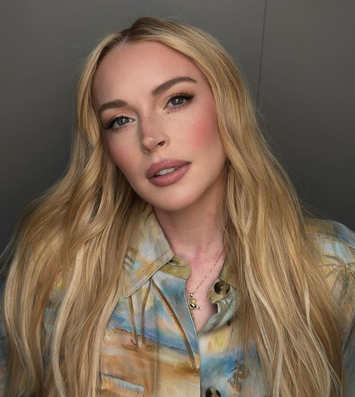 Lindsay Lohan stuns with her look and missing freckles in a close-up portrait wearing a patterned shirt and subtle makeup.