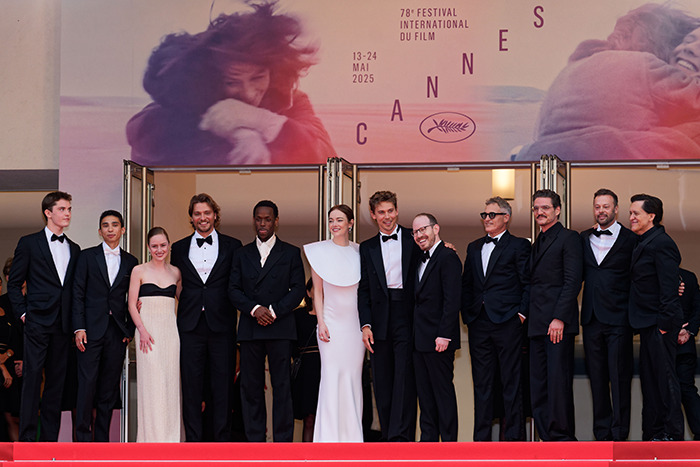 Group of actors posing on Cannes red carpet, with lip reader decoding Pedro Pascal&rsquo;s hand wave to Joaquin Phoenix.