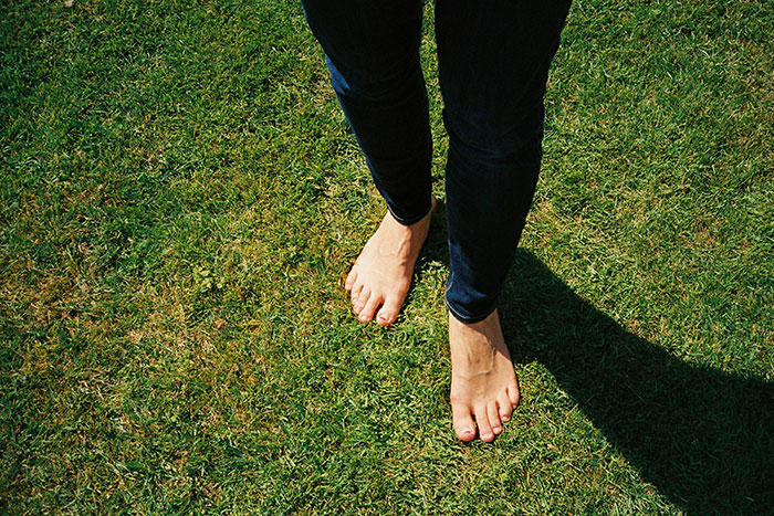 Bare feet on grass, symbolizing people using the anonymity of the internet to share their secrets freely.