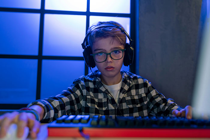 Teen boy wearing glasses and headphones using a computer, illustrating people sharing dirty little secrets online anonymously.