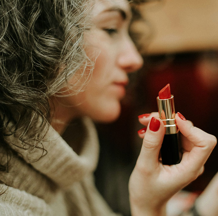 Woman holding red lipstick near face, symbolizing people using internet anonymity to share dirty secrets.