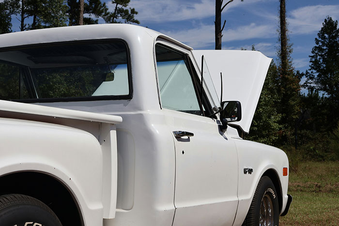 White vintage pickup truck with its hood open parked outdoors among trees on a clear day representing internet anonymity concept