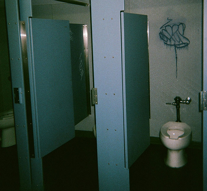 Public restroom stalls showing graffiti, symbolizing how people use internet anonymity to share secrets discreetly.