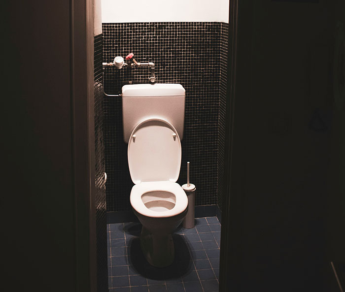 Toilet in a dimly lit small bathroom, symbolizing people using the anonymity of the internet to share secrets.