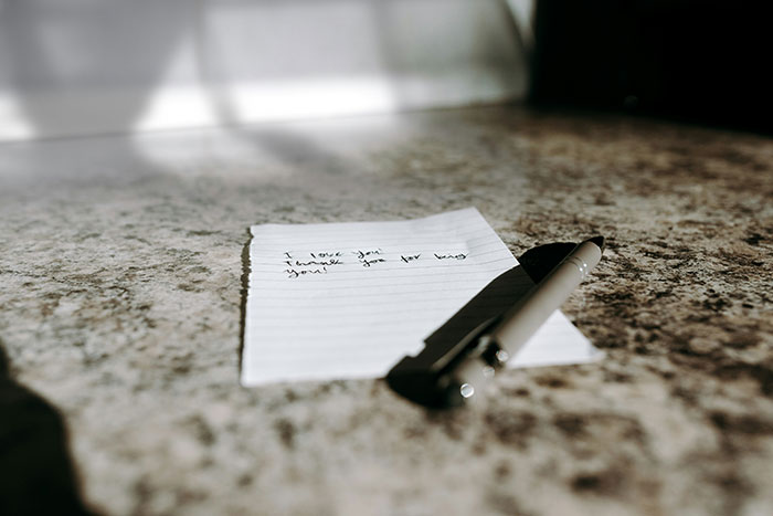 Pen resting on a handwritten note on a stone surface, symbolizing people sharing their dirty little secrets anonymously.