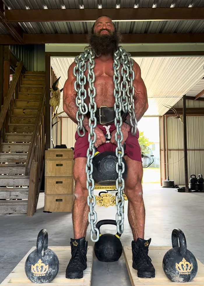 Muscular man with long beard lifting kettlebell wrapped in heavy chains in a gym, related to raw animal diet and Liver King. Muscular man with long beard lifting kettlebell wrapped in heavy chains in a gym, related to raw animal diet and Liver King.