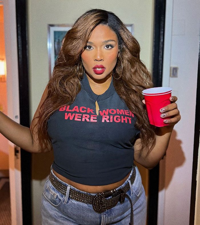 Lizzo wearing a sleeveless top and jeans, holding a red cup, showing off her body after hitting weight loss goal. Lizzo wearing a sleeveless top and jeans, holding a red cup, showing off her body after hitting weight loss goal.