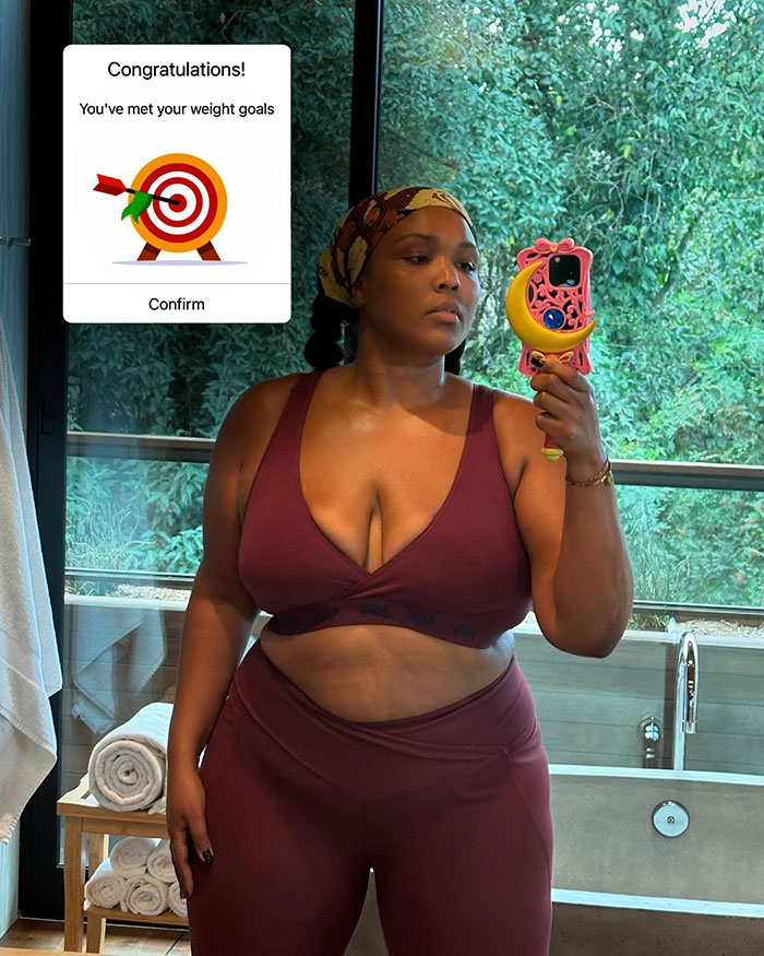 Lizzo taking a mirror selfie in a sports bra and leggings showing off body after hitting weight loss goal. Lizzo taking a mirror selfie in a sports bra and leggings showing off body after hitting weight loss goal.