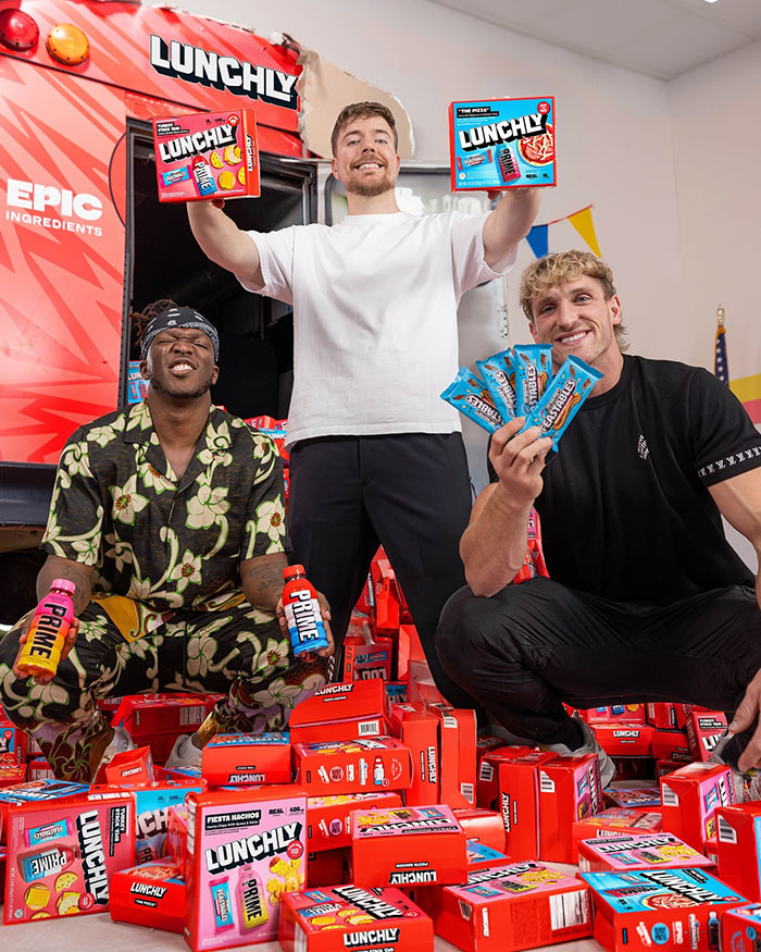Three men icluding Logan Paul surrounded by Lunchly and Prime products, highlighting Logan Paul net worth after Prime business ventures.