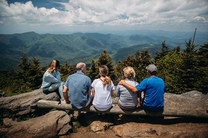 A family of five sitting on a log overlooking mountains, symbolizing reconnecting with a long-lost grandfather.
