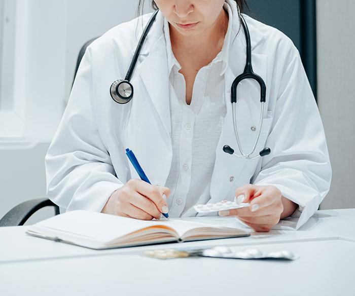 Woman medical professional holding pills and writing notes, illustrating change after losing pretty privilege concept.