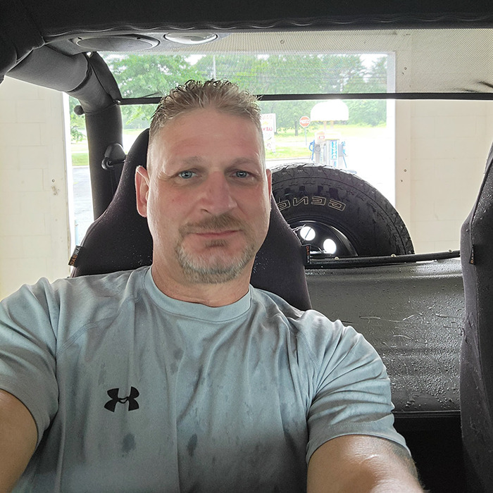 Man in a light gray shirt sitting inside a vehicle, related to Ashish Yadav dad fatally beaten with metal bat news.
