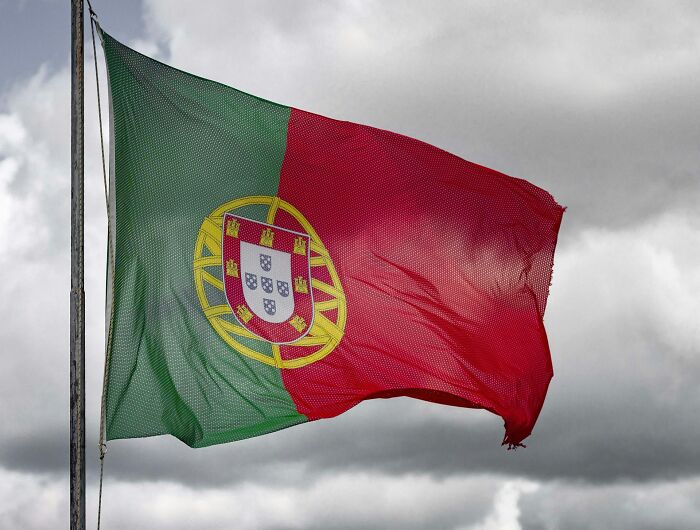 Portuguese flag waving against a cloudy sky representing new facts and today I learned posts questioning reality.