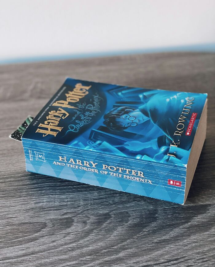 Paperback book titled Harry Potter and the Order of the Phoenix on a wooden surface representing shocking experiences theme.