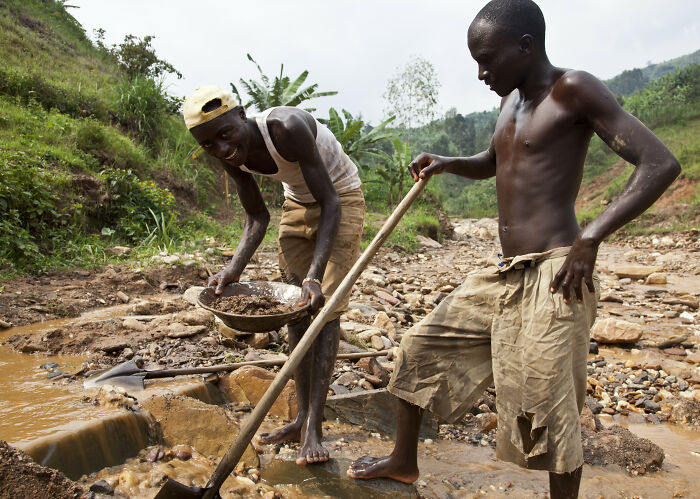 Two men working in a riverbed with a shovel and pan, highlighting a major event happening today not covered by media.