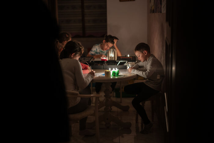 Children studying by candlelight in a dim room, highlighting a major event happening today not covered by media.
