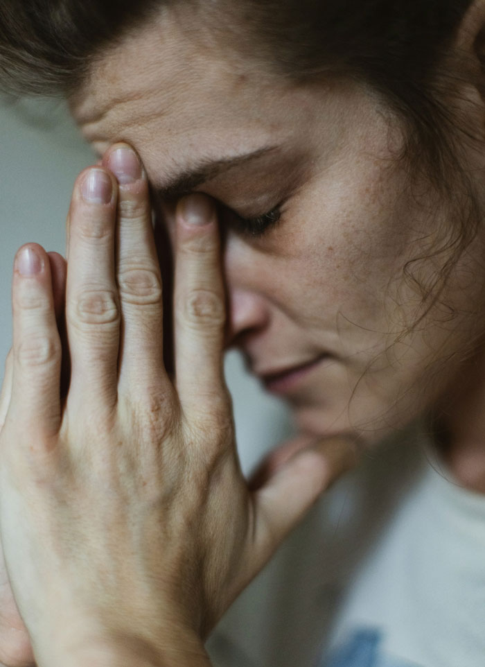 Woman with eyes closed and hands near face, showing emotion after traumatic birth experience, feeling misunderstood by boyfriend.