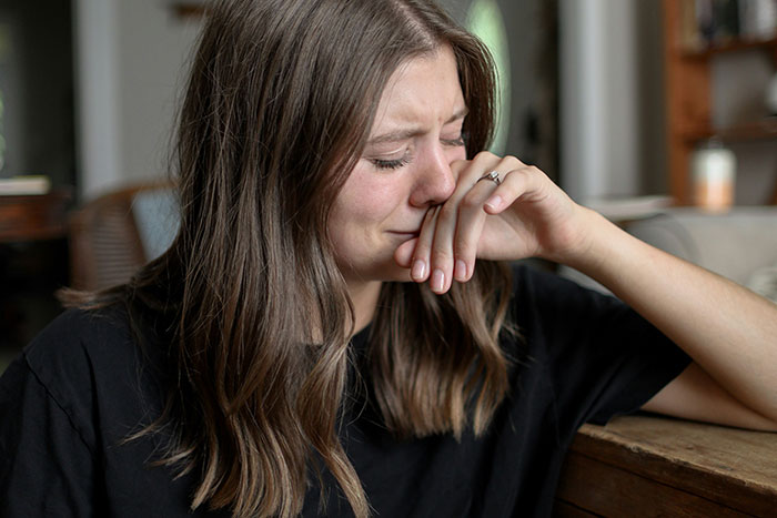 Young woman upset and crying at home, reflecting the stress of bride-to-be shutting down prenup over secret credit card debt.