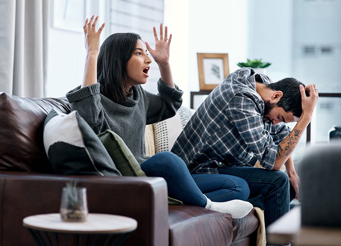 Couple having a tense argument on a couch, illustrating confession of faking a twin brother to ghost a girl. Couple having a tense argument on a couch, illustrating confession of faking a twin brother to ghost a girl.