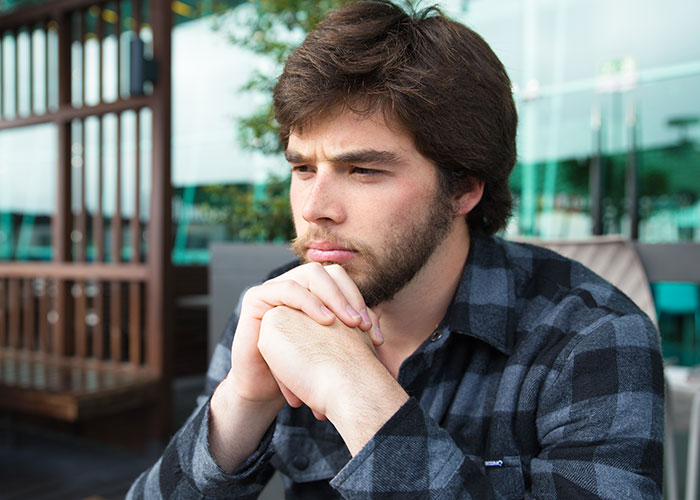 Young man looking thoughtful and upset, sitting with hands clasped, reflecting on relationship and fake pregnancy test of love. Young man looking thoughtful and upset, sitting with hands clasped, reflecting on relationship and fake pregnancy test of love.