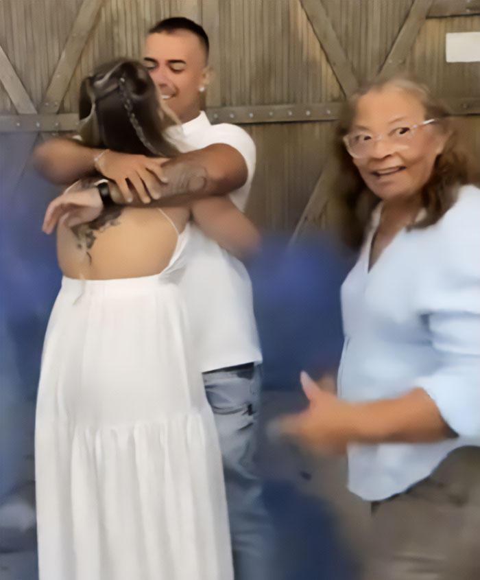 Man hugging wife during baby gender reveal while mom looks on, highlighting man pushes mom away controversy.