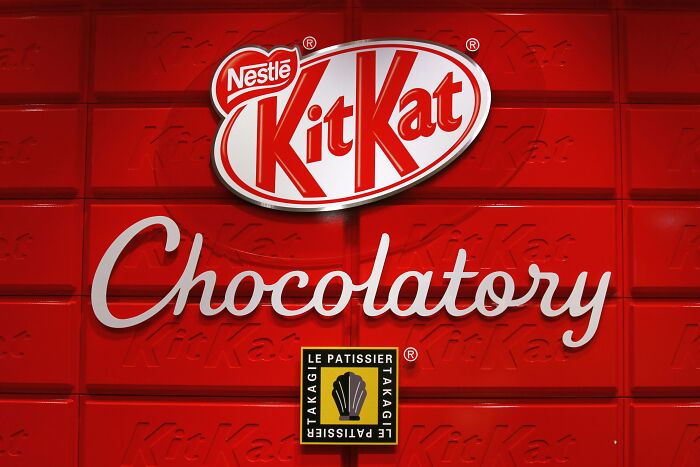 KitKat Chocolatory brand logo on red background, related to people share companies bad list discussion.