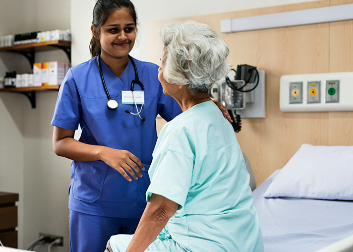 Medical worker pretending to be calm while comforting an elderly patient in a hospital room setting.