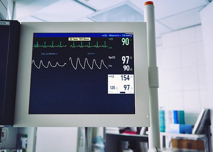 Medical workers monitoring vital signs on a hospital heart rate and oxygen saturation monitor screen.