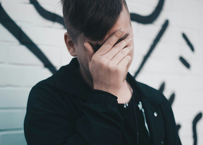 Young man covering his face in disbelief, illustrating medical workers pretending to be calm while seeing something unbelievable.