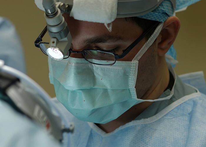 Medical worker wearing surgical mask and glasses focused during a procedure, illustrating calm in an unbelievable moment.