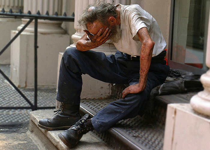 Older man sitting on steps with hand covering his face, appearing stressed or overwhelmed, illustrating medical workers staying calm.