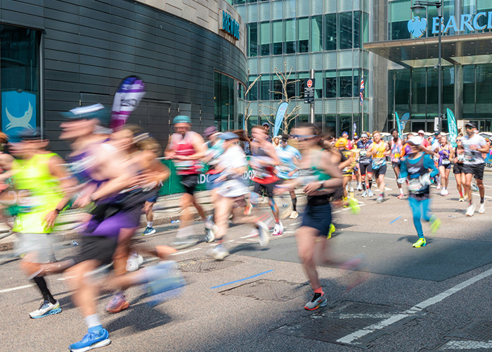Blurred runners in motion during a city marathon with medical workers on standby for emergencies and support.