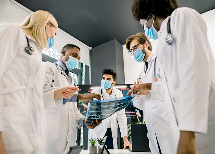 Medical workers wearing masks examining X-ray scans while pretending to stay calm in a clinical setting.