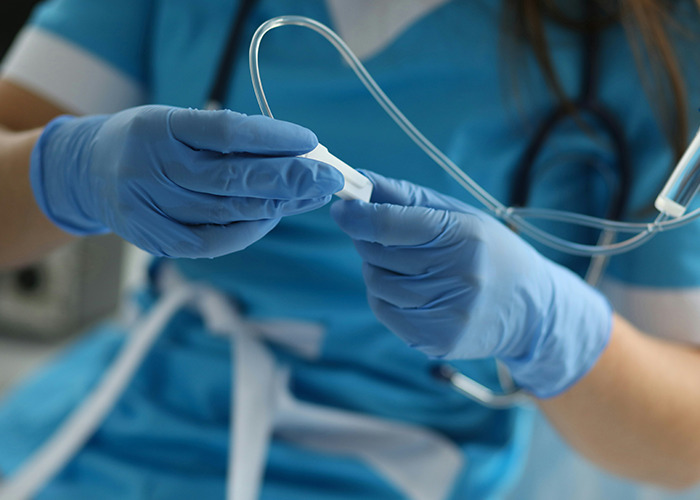 Medical worker wearing blue gloves handling medical tubing, showing calmness while seeing something unbelievable