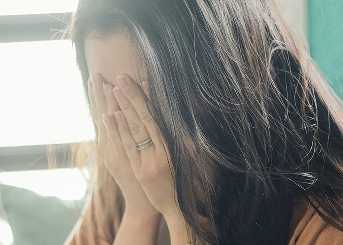 Medical worker covering face with hands, pretending to be calm while witnessing something unbelievable indoors.
