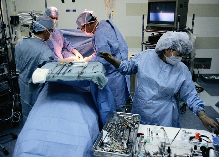 Medical workers in surgical scrubs performing an operation, staying calm while handling medical tools and instruments.