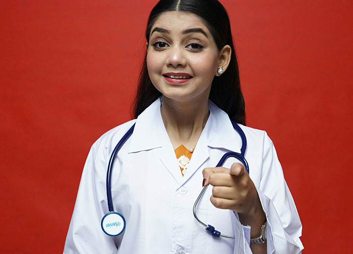 Young female doctor in white coat with stethoscope pointing, representing hurtful things doctors said that made patients change doctors