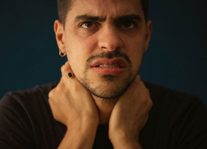 Man with distressed expression holding his neck, representing hurtful things doctors said that made patients want to change doctors