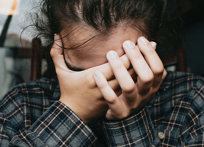Person covering their face with hands expressing distress after hurtful things doctors said causing patients to change doctors